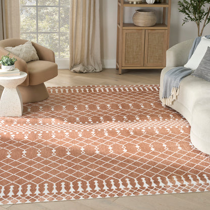 Rust-orange geometric lattice area rug with white accents anchors a cozy living room with a tan lounge chair and beige sofa.