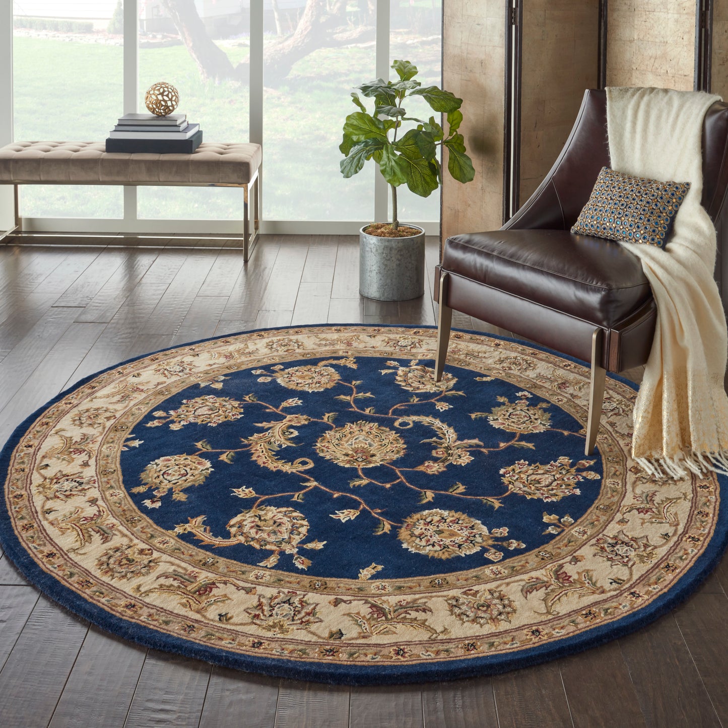 Round blue and beige ornate rug with floral medallions in a modern living room beside a leather armchair.