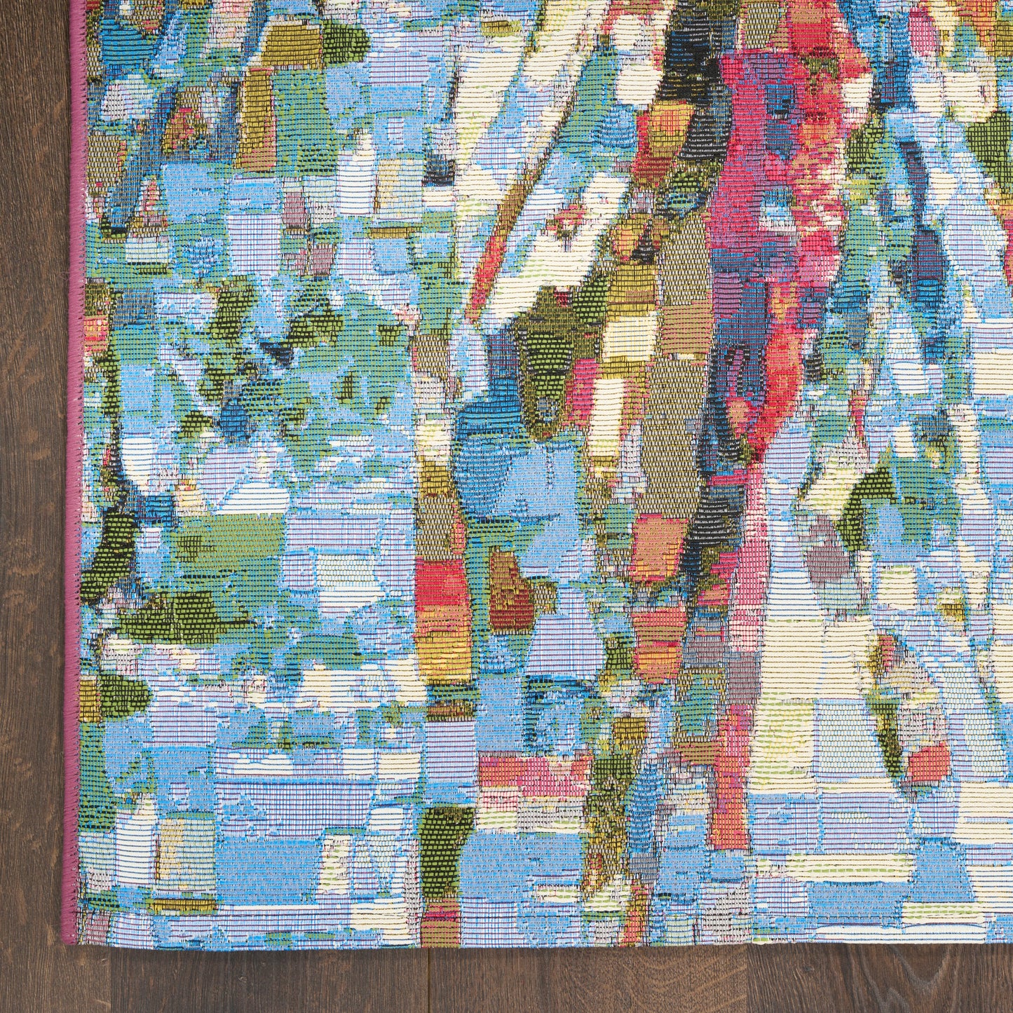 Vibrant abstract woven rug with multicolor mosaic blocks in blues, greens, yellows and pinks; pink edge trim.