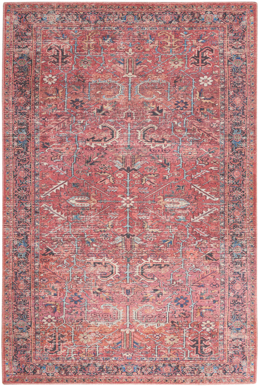 Pink oriental rug with blue and ivory floral vines and geometric motifs, bordered by a detailed multi-colored border.