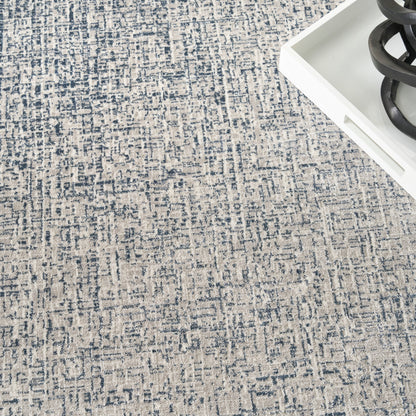 Blue & beige abstract patterned woven area rug with textured pile; paired with a white tray & black spiral decor.