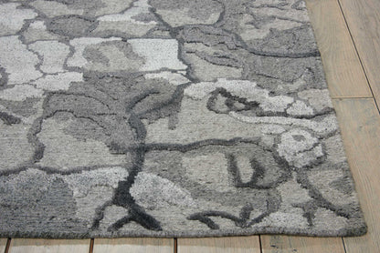 Soft grey shag rug with abstract dark and light grey patterns on wood flooring.