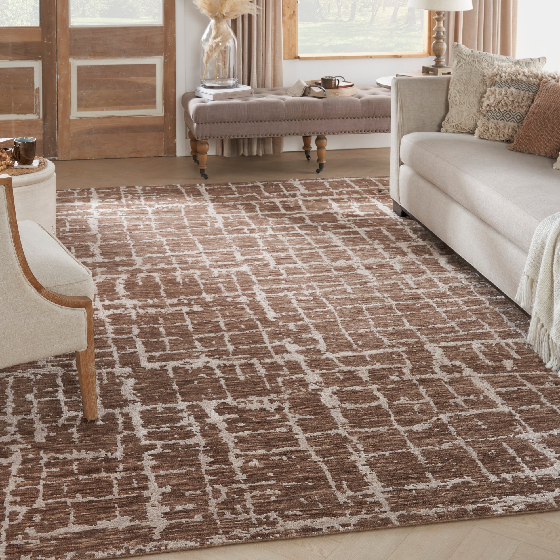 Brown rug with white grid pattern in a sunlit living room, paired with beige sofas and light wood furniture.