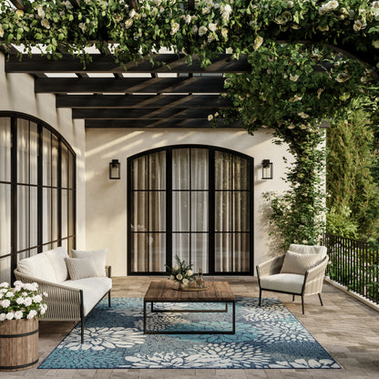 Outdoor patio with arched black-framed glass doors, wicker seating, blue floral rug (6' x 9'), wooden coffee table, climbing vines