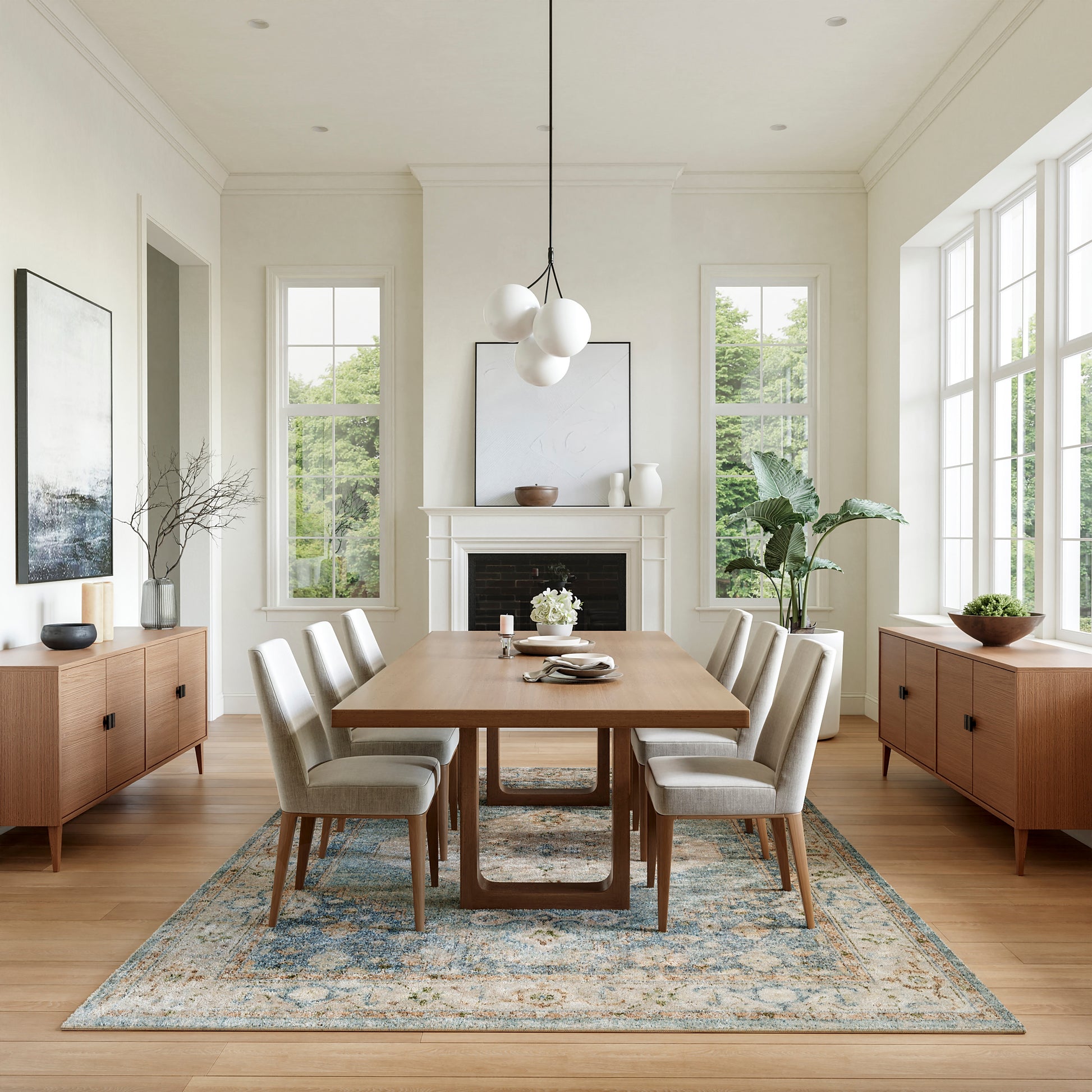 Bright dining room with rectangular wood table, six beige upholstered chairs, blue-toned rug, and globe pendant light.