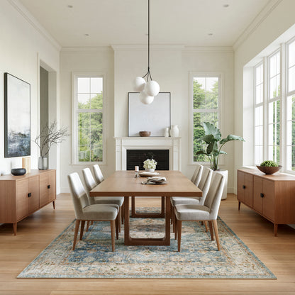 Bright dining room with rectangular wood table, six beige upholstered chairs, blue-toned rug, and globe pendant light.