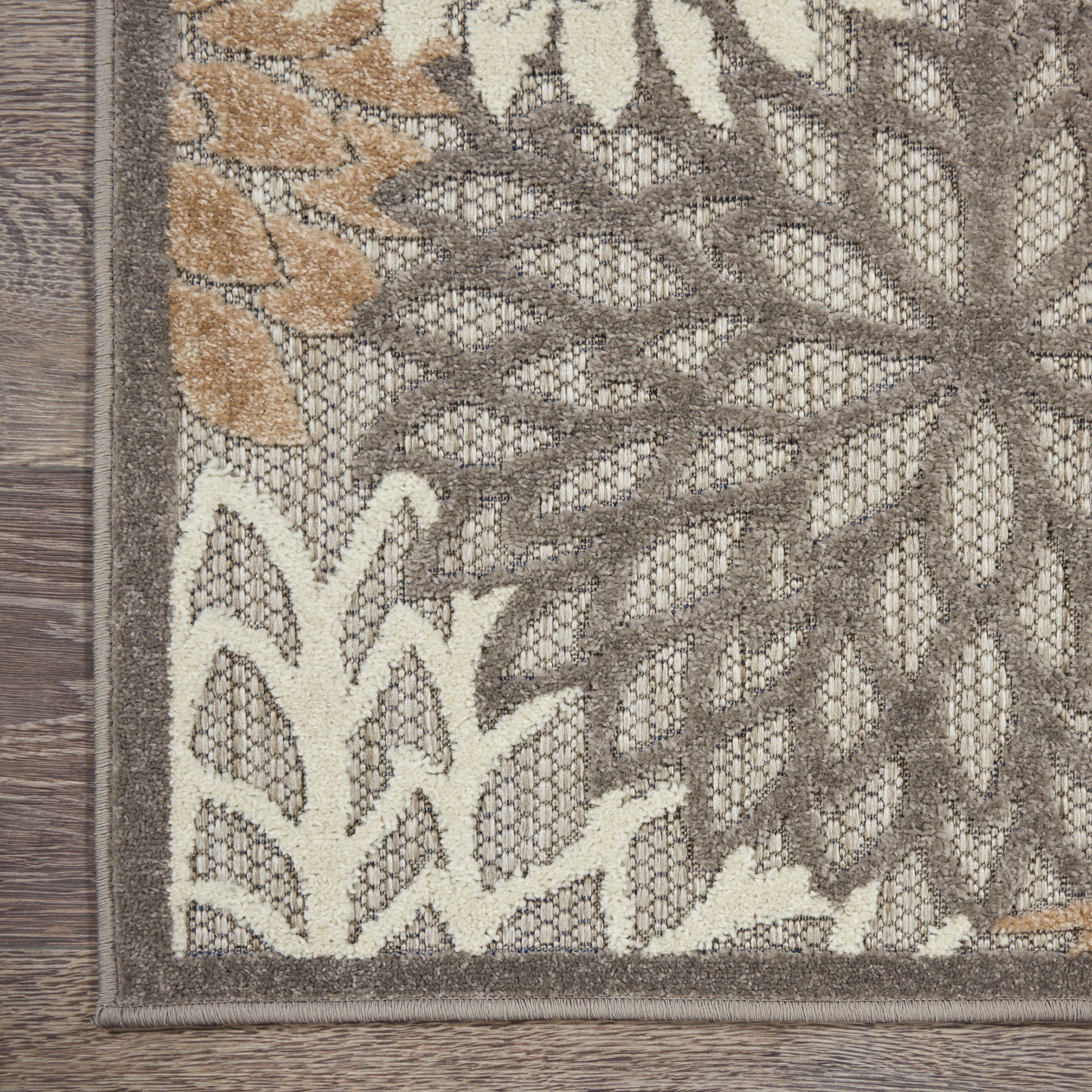 Neutral woven area rug with grey, taupe and ivory botanical leaf pattern and dark border.