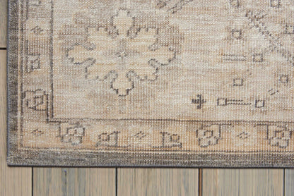 Beige-gray traditional oriental rug with a floral medallion & decorative border on a wooden floor.