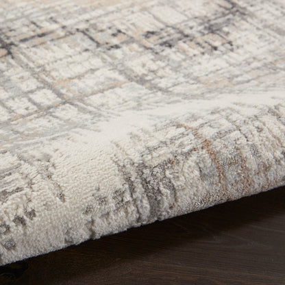Neutral-toned plush rug with a geometric pattern and folded edge on dark wood floor.