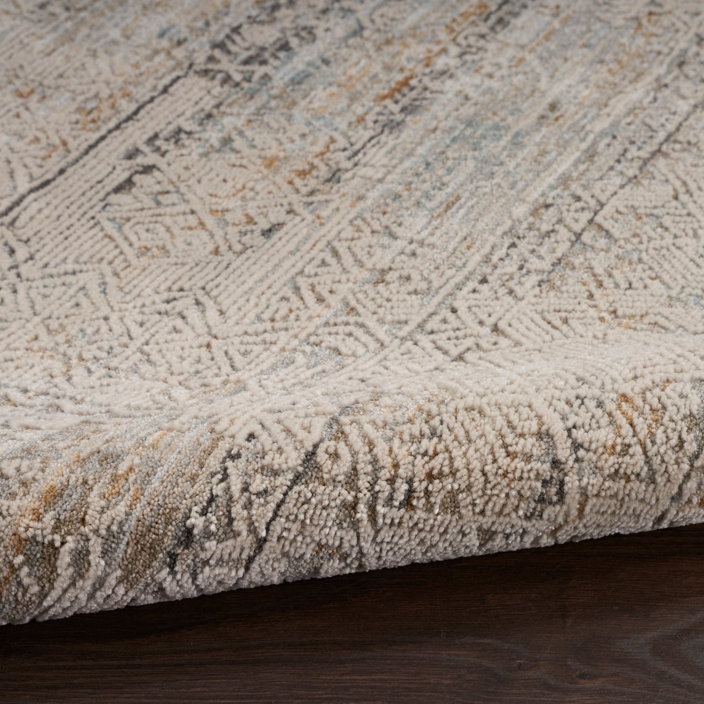 Beige-gray geometric runner rug with blue and tan accents, thick looped pile, rolled edge on dark wood floor.