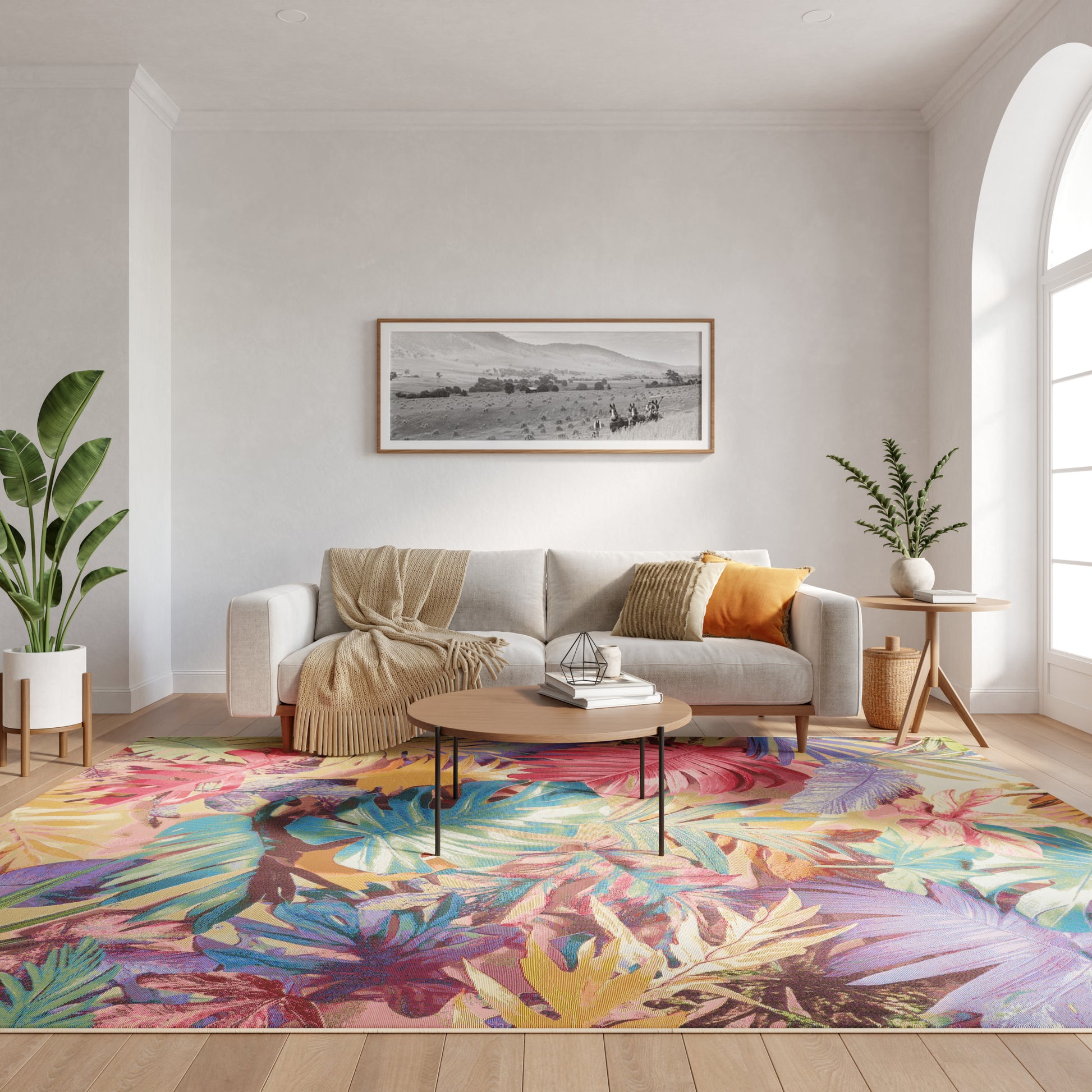Cozy living room with beige sofa, knit throw, round wood coffee table, tropical leaf rug, plants, arched window.