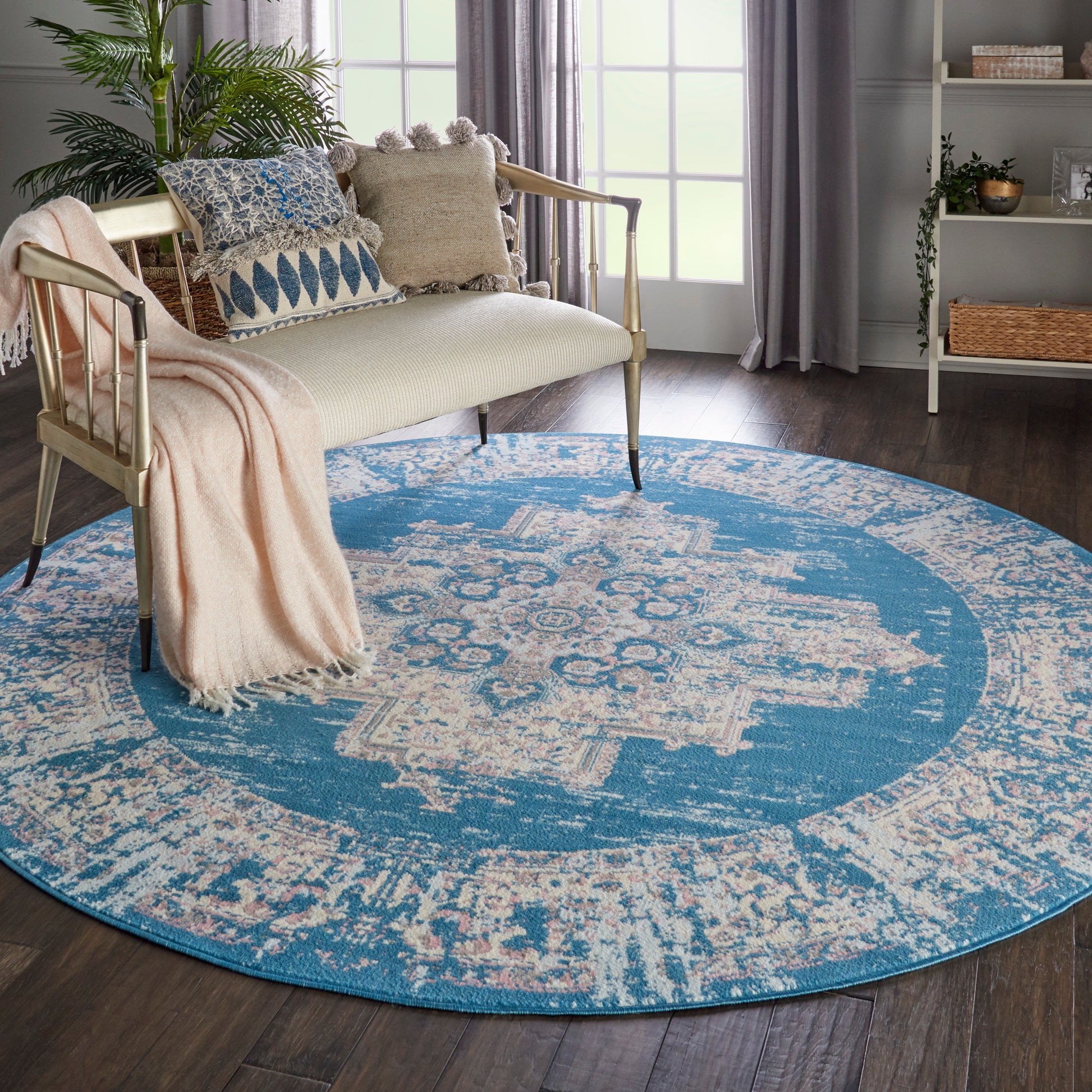 Round blue area rug with ivory distressed geometric pattern in a cozy living room with a beige sofa and plants.