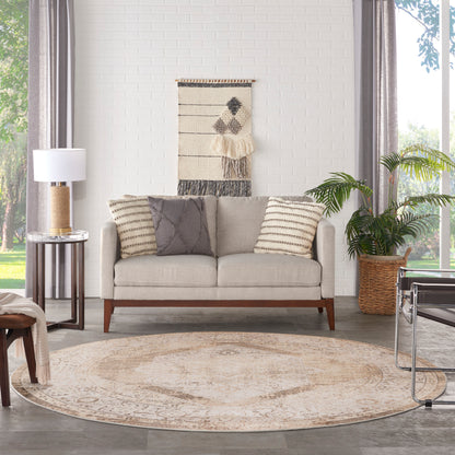 Beige sofa with striped and solid cushions, round beige rug, woven wall hanging, potted plant in basket.