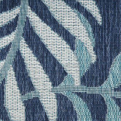 Close-up of navy and teal woven rug with a geometric leaf-like pattern and textured jacquard weave.