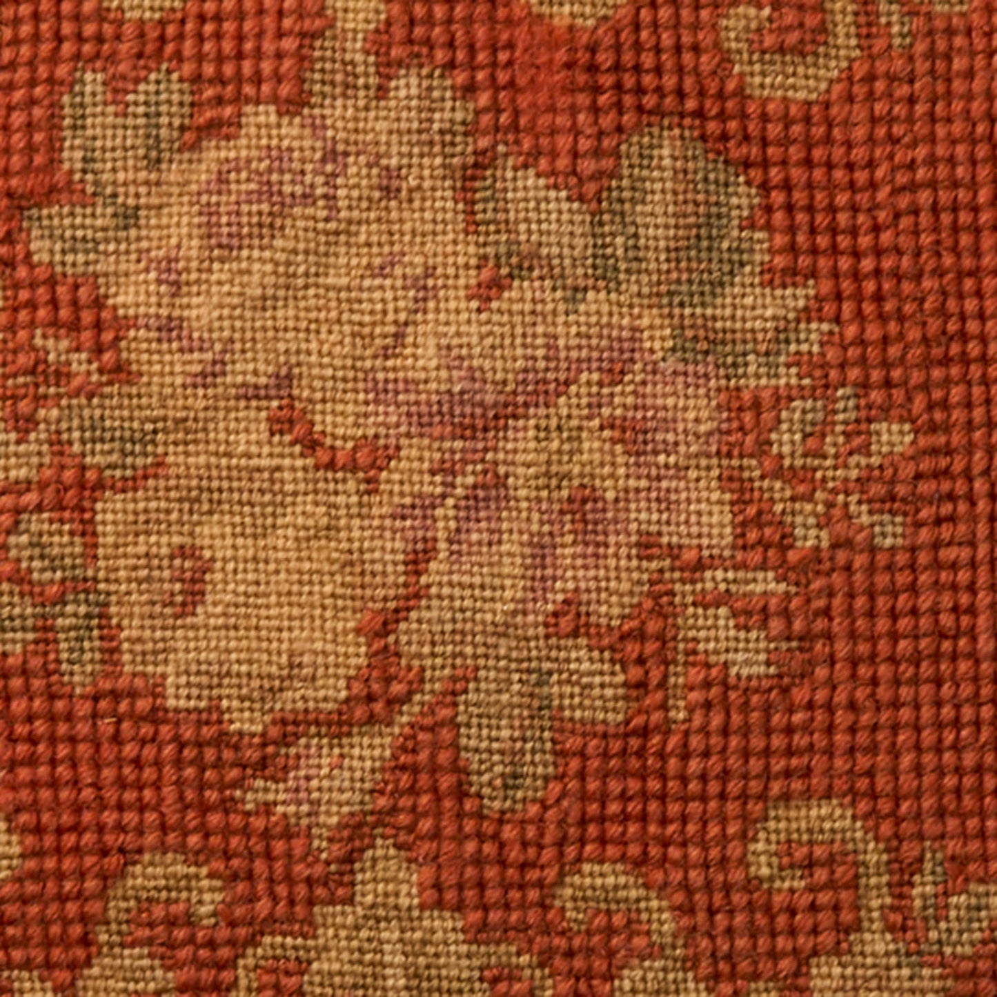 Rust-orange woven rug with beige floral motif; textured tapestry fabric.