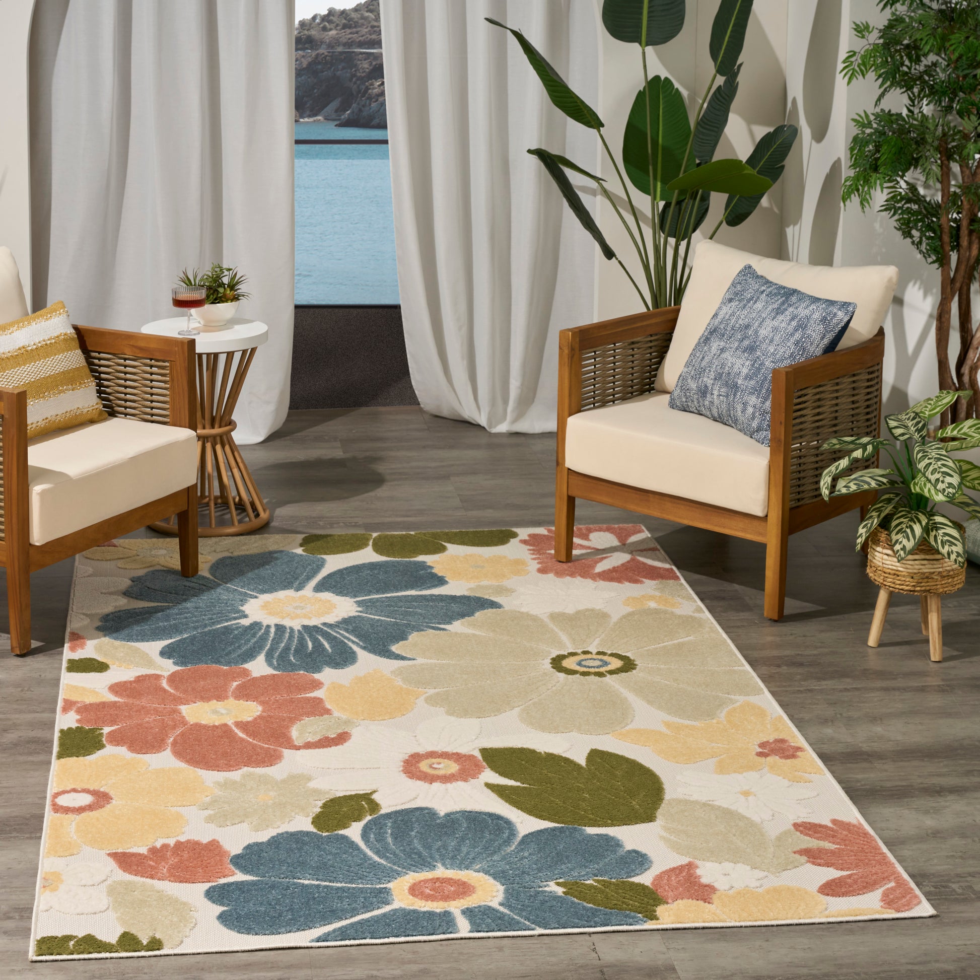 Colorful floral area rug with large blue, yellow, coral flowers; wood-framed chairs with cushions in a living room.