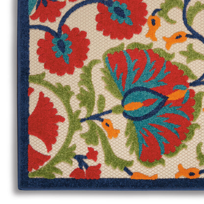 Close-up of a decorative floral rug corner with red, blue and green petals on a beige woven background and a navy border.