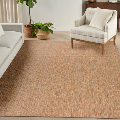 Natural woven jute area rug in a living room with beige striped armchair, light sofa, and potted plants.