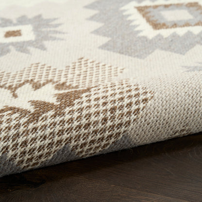 Close-up of a beige-brown-gray geometric woven rug with diamond motifs and textured surface.