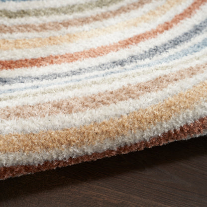 Close-up of a plush shag rug with tan, cream, blue and orange stripes on a dark wood floor.