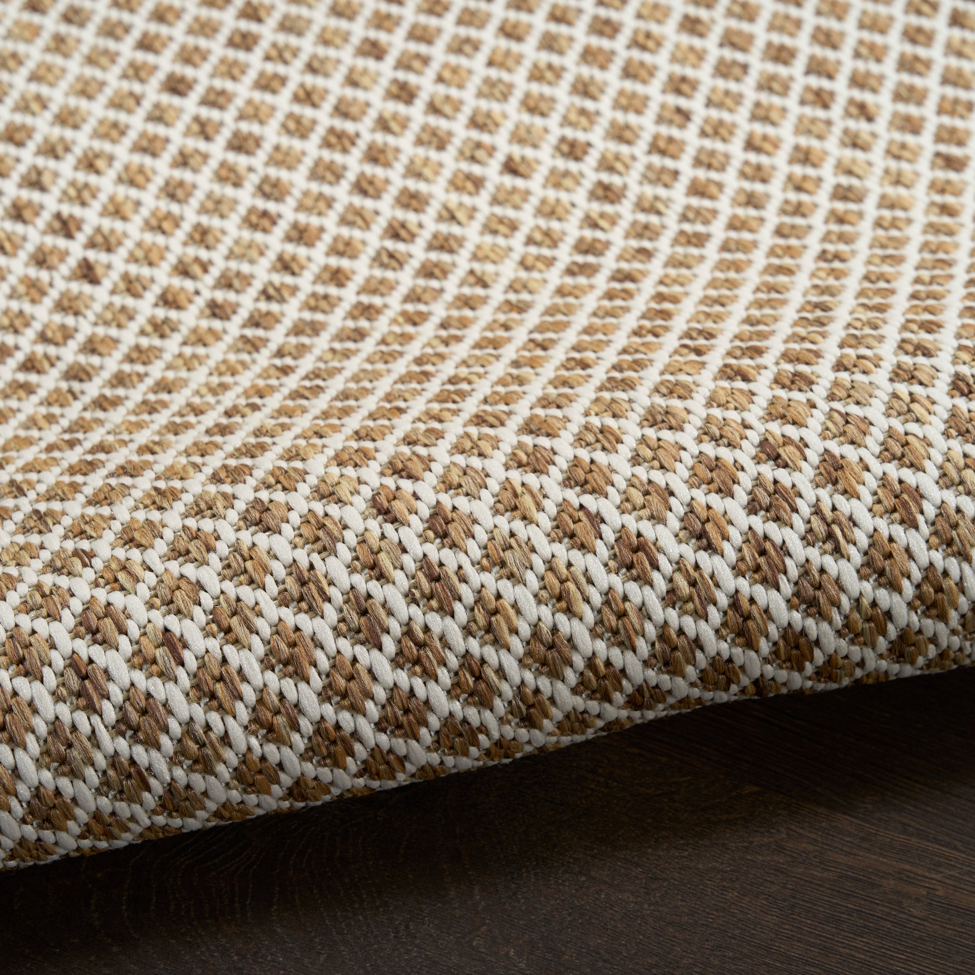 Beige and white woven rug fabric with a rustic basket-weave texture and folded edge.