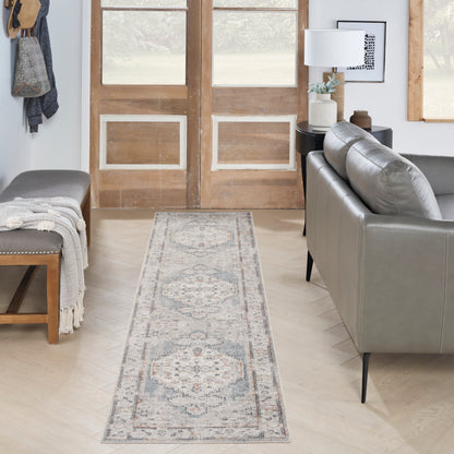 Light blue-gray Persian-style runner rug with beige motifs on pale wood floor; modern living room with gray sofa & bench.