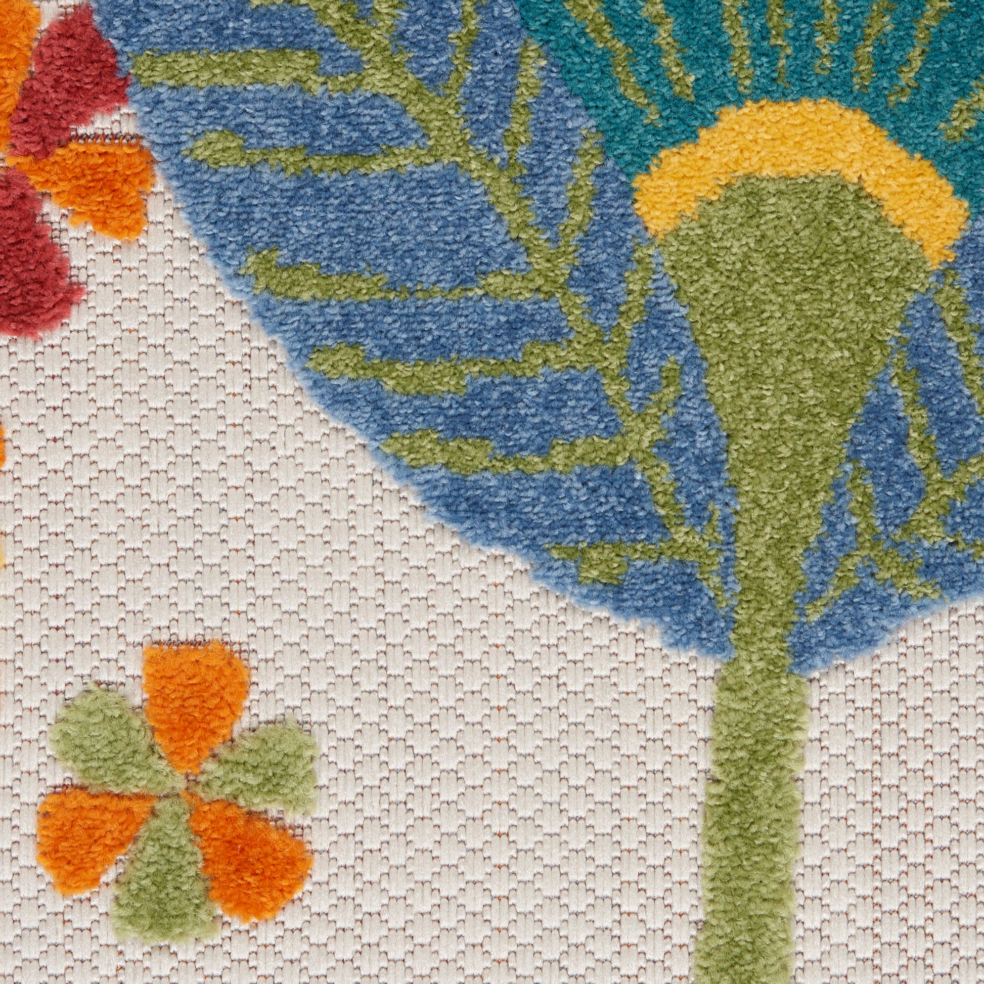Close-up of a textured woven rug with a large blue flower motif, lime-green stem, yellow center, and small orange petals on beige.