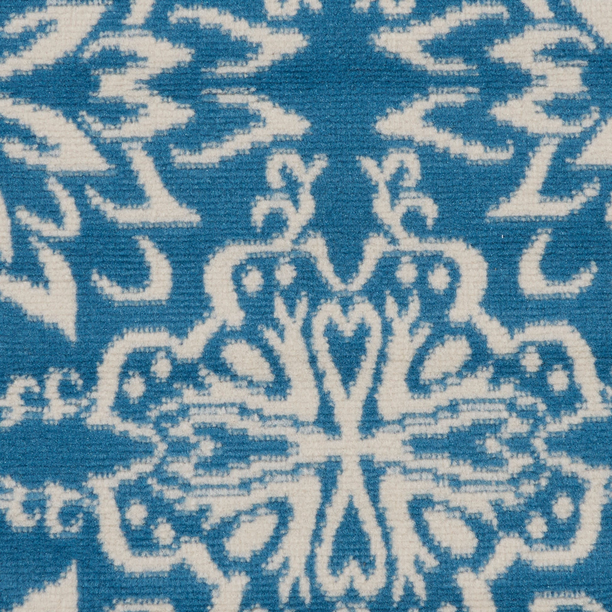 Blue fabric with white ornate damask floral pattern; woven textile with a central medallion motif.