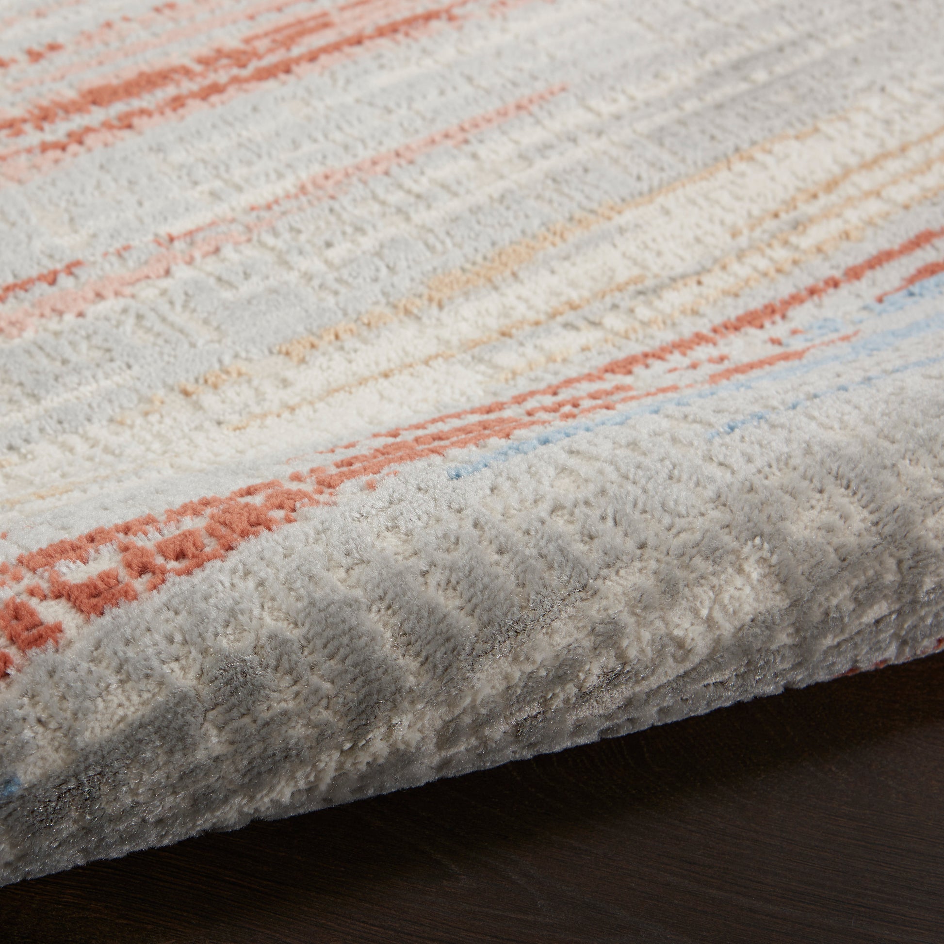 Soft abstract striped rug in pastel blue, peach, gray and cream with a plush tufted pile.