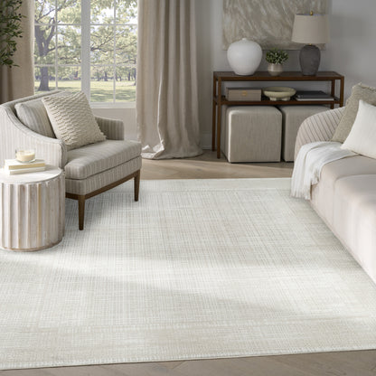 Neutral living room with cream textured rug, beige sofa and armchair, round ribbed side table, wooden console.