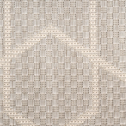 Beige-gray textured woven rug with a raised block pattern and circular motif.