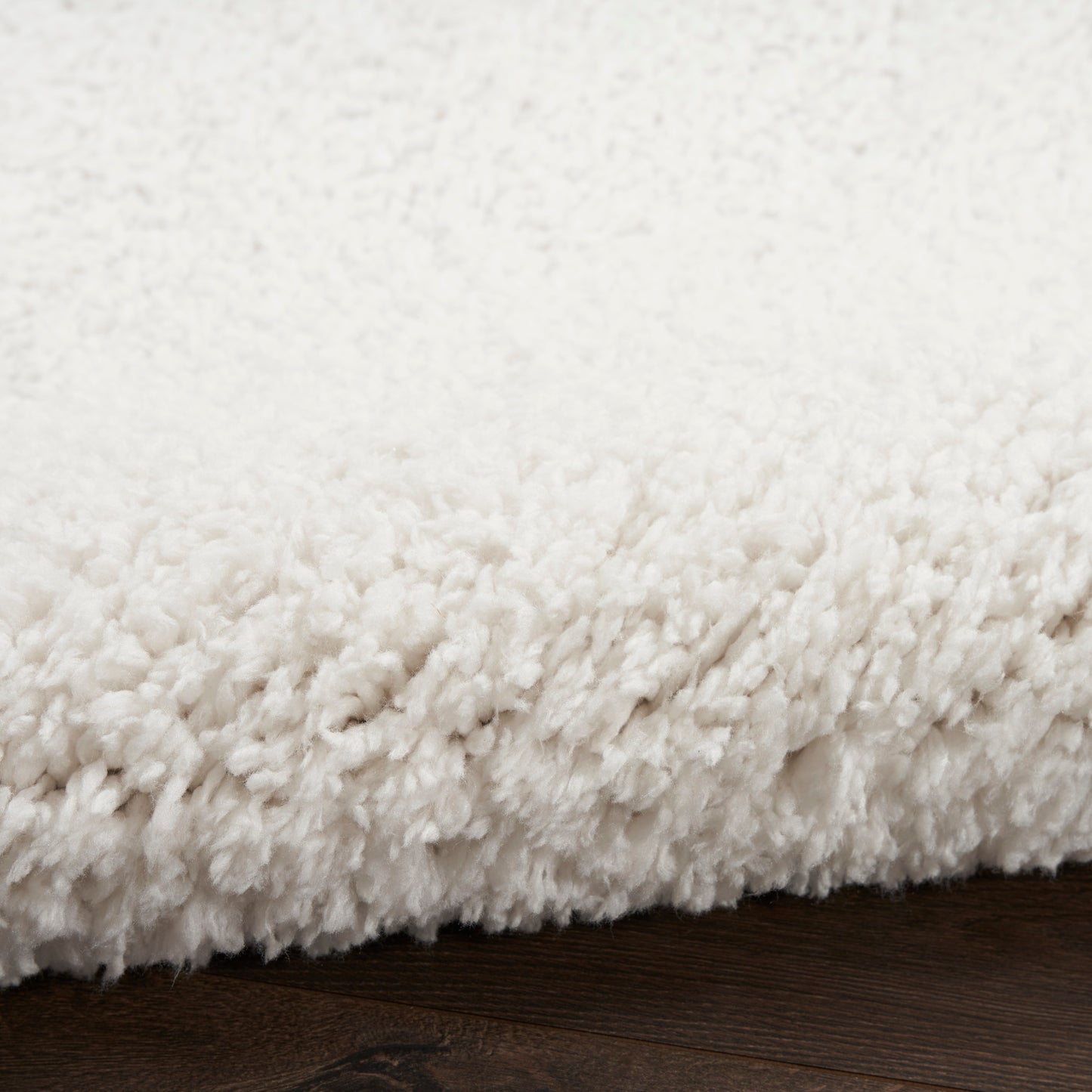 Cream white plush shag rug with thick pile on dark wooden floor