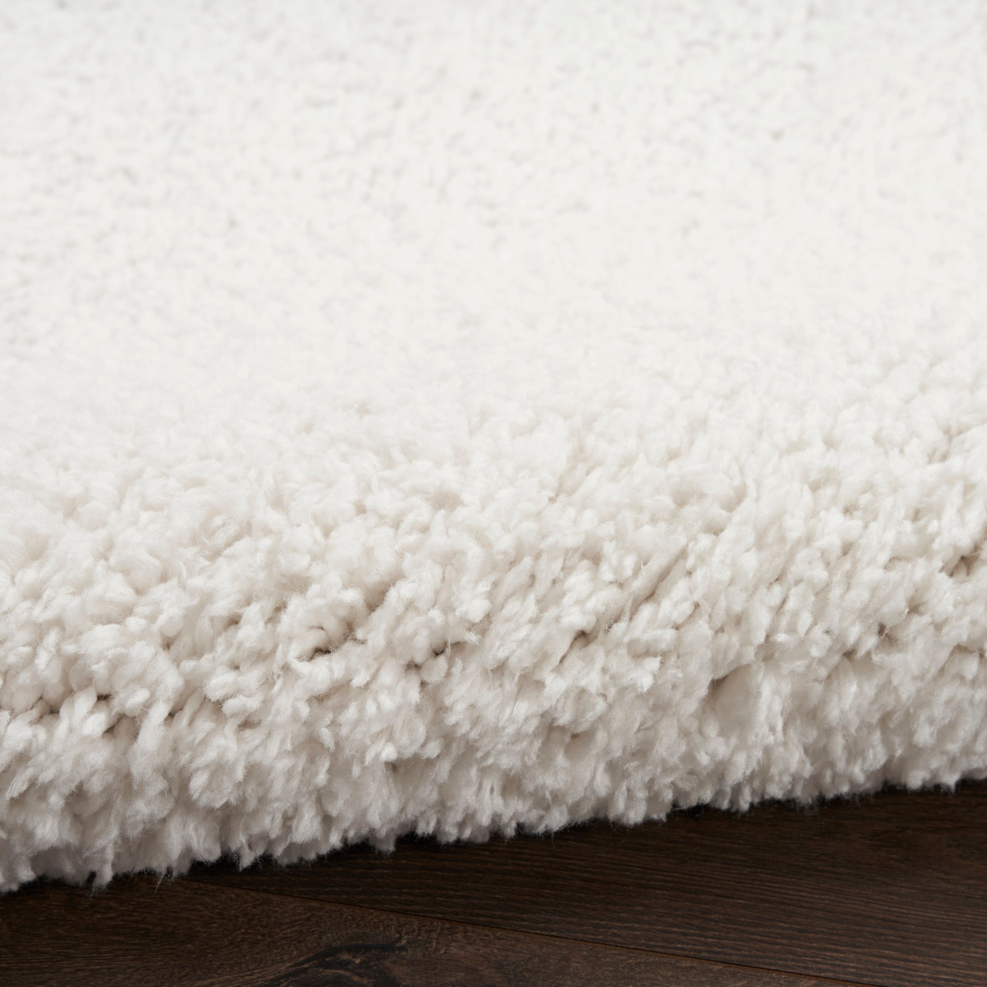 Cream white plush shag rug with thick pile on dark wooden floor
