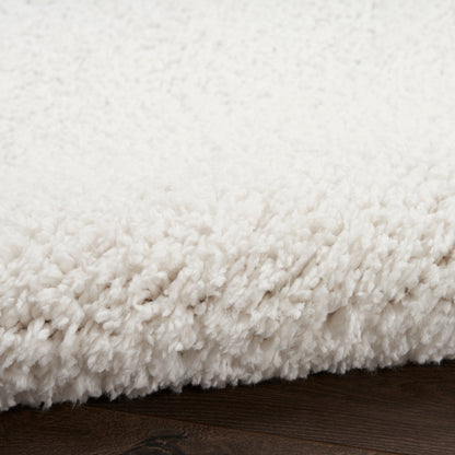 Cream white plush shag rug with thick pile on dark wooden floor