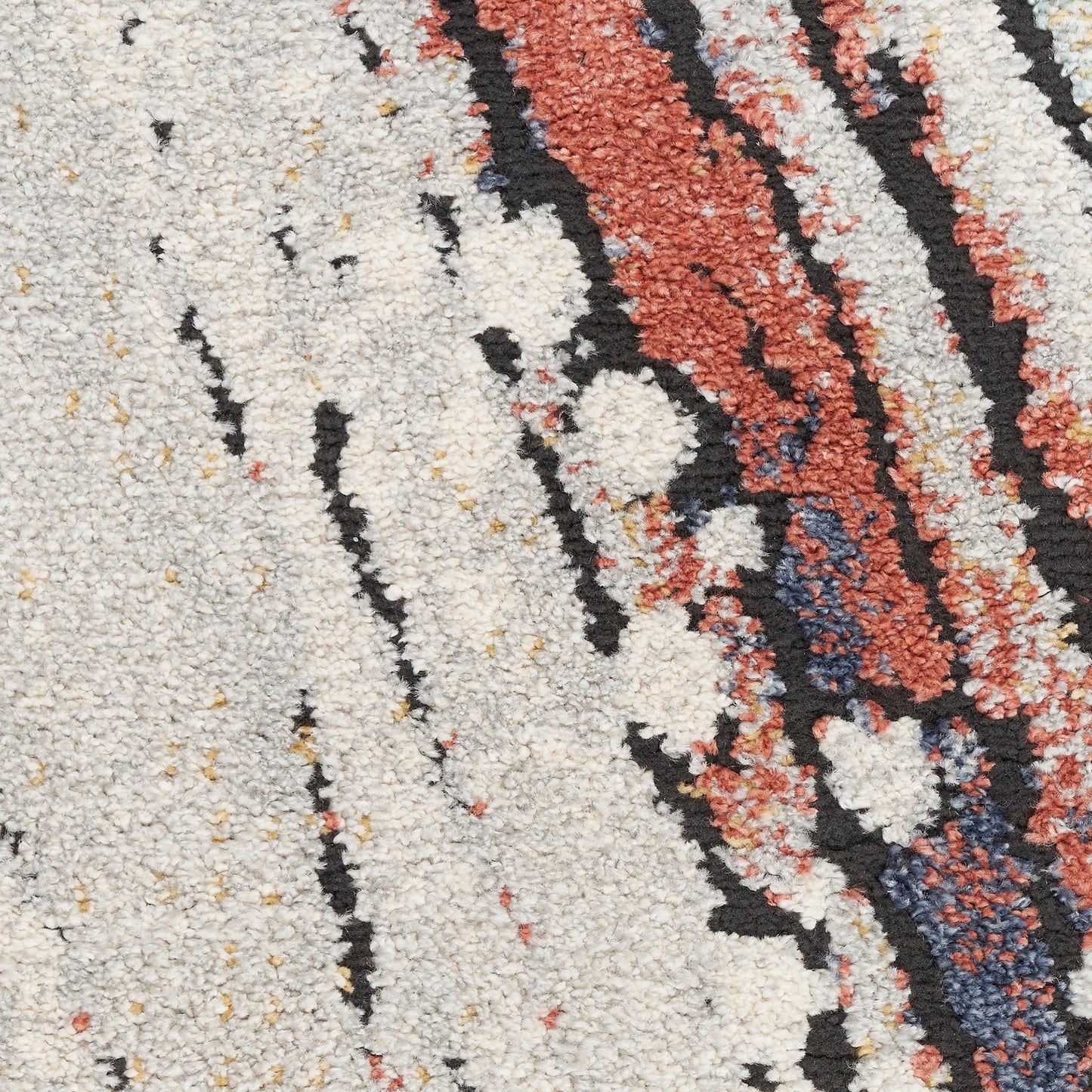 Close-up of a cream shag rug with abstract black, rust and navy stripes and a textured loop-pile.