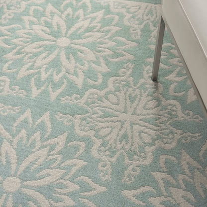 Turquoise rug with a large white floral/starburst pattern; soft woven texture, farmhouse style.