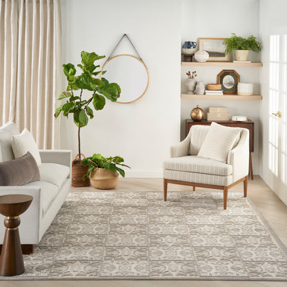 Neutral living room with beige sofa, striped armchair, large leafy plant, round wall hoop, wooden shelves and patterned rug.