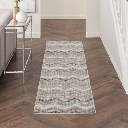 Long neutral-toned runner rug with wavy chevron pattern on wood hallway floor, beside a chrome console table.