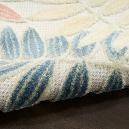 Cream rug with blue leaf-pattern, plush pile texture, folded edge showing thick weave, on dark wood floor.