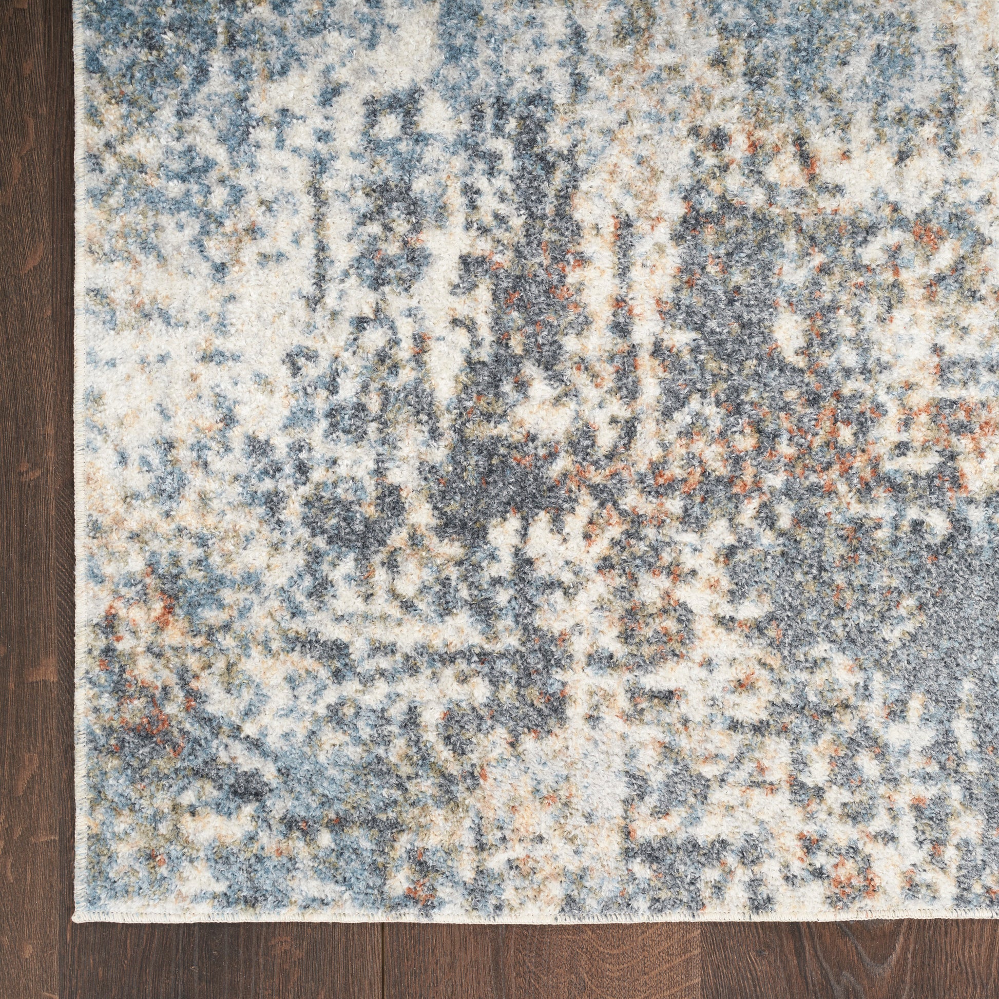 Abstract blue-gray and cream rug with mottled pattern on dark wood floor; modern, textured area rug.