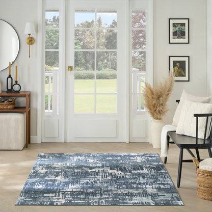 Bright living room with blue abstract rug, light wood floors, white French doors, neutral seating, pampas decor.