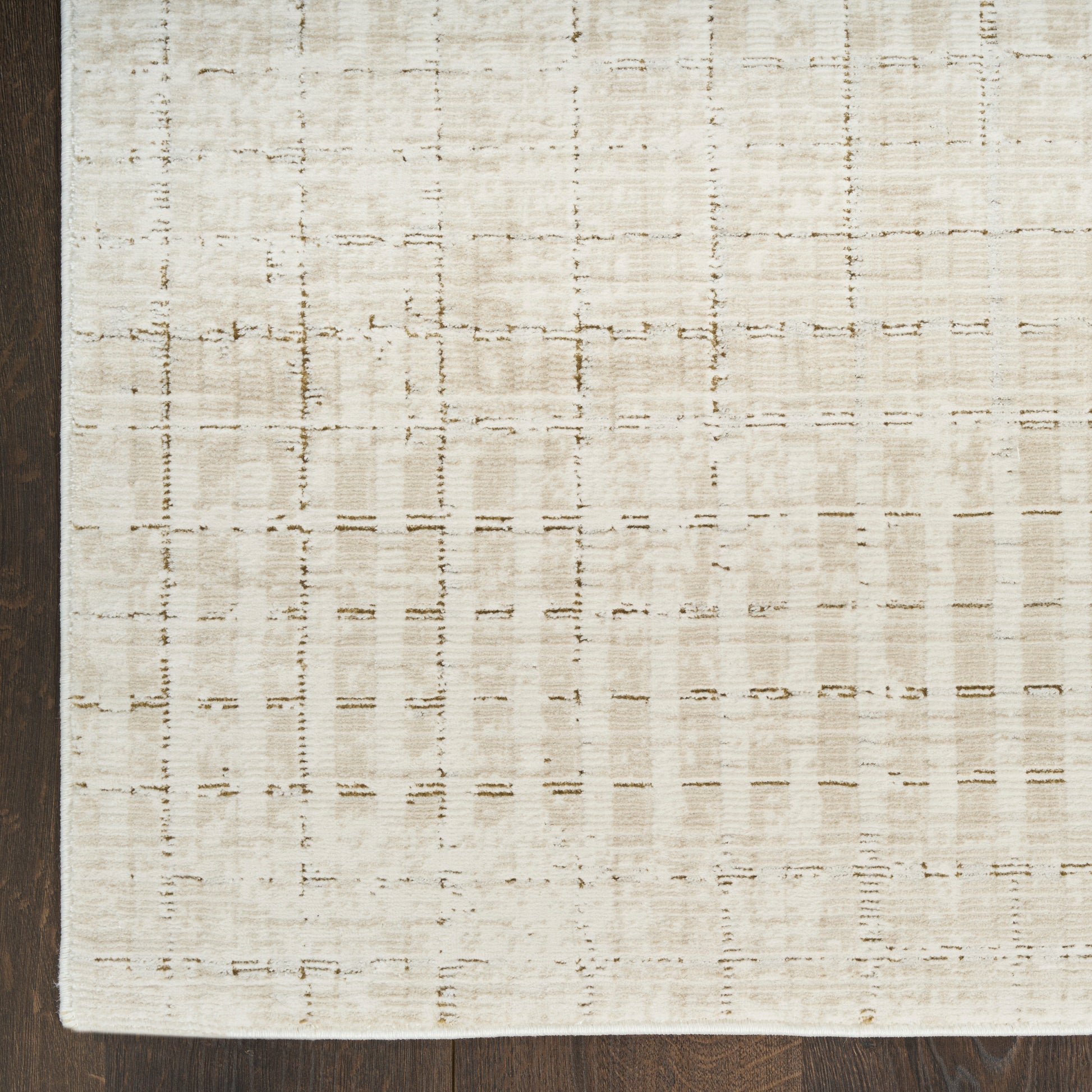 Cream flatwoven rug with a subtle tan grid pattern on a dark wood floor.