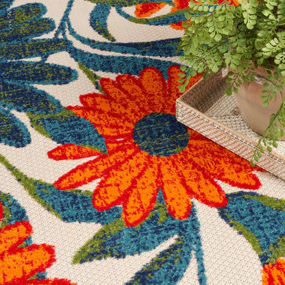 Bright floral outdoor rug with large orange petals and blue-green leaves.
