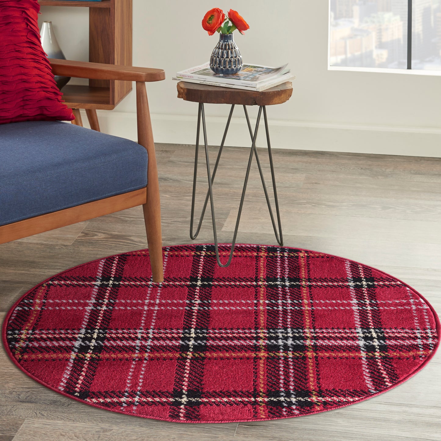 Round red plaid rug with black-and-white lines under a metal-hairpin-leg side table; blue cushioned wooden chair nearby.