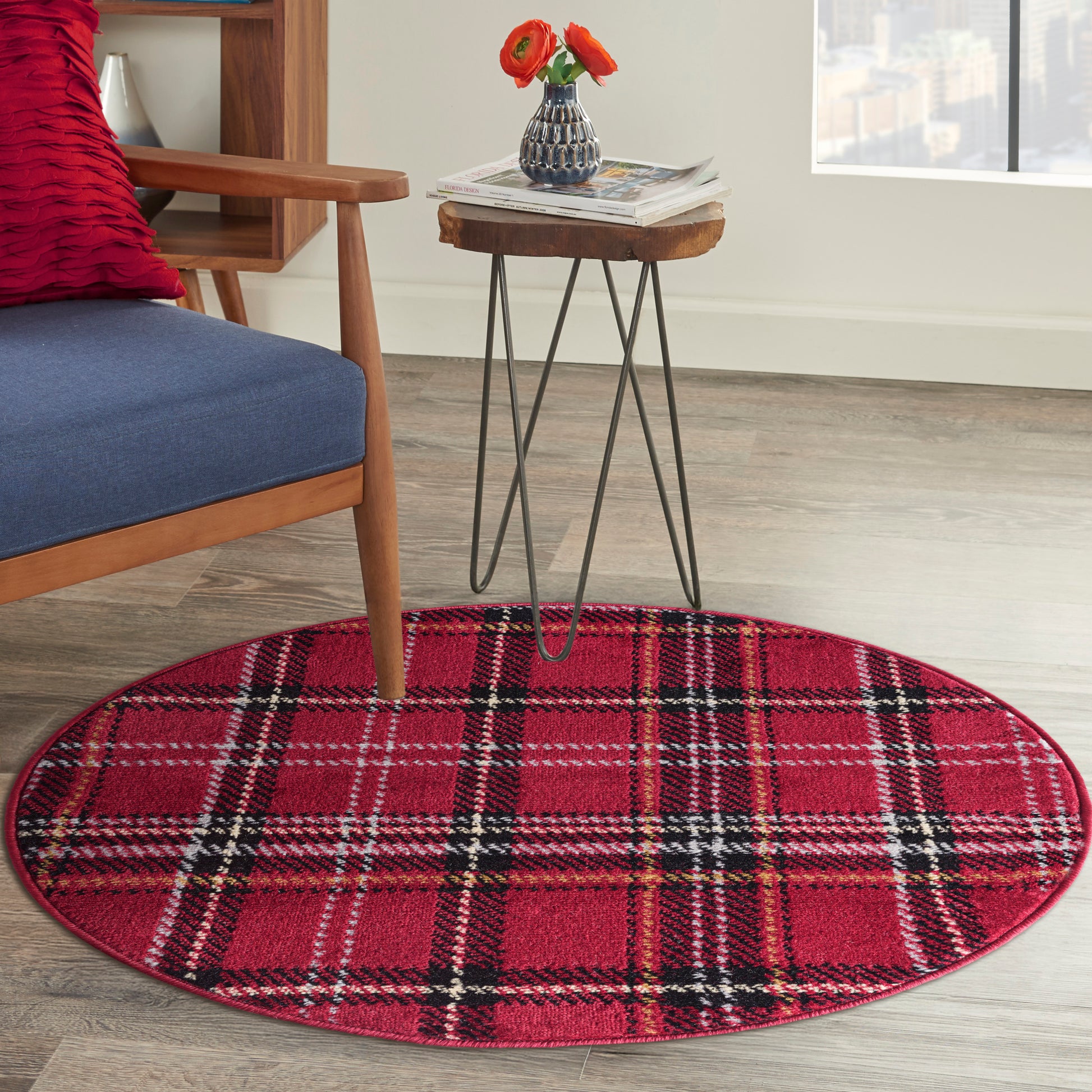 Round red plaid rug with black-and-white lines under a metal-hairpin-leg side table; blue cushioned wooden chair nearby.