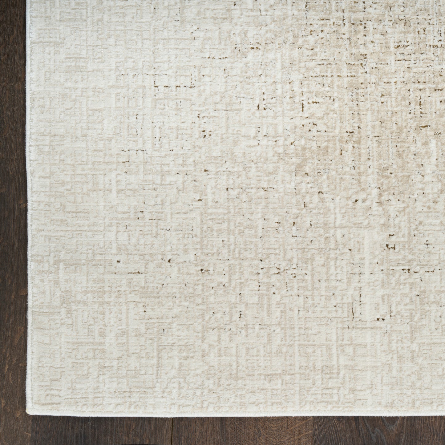 Beige textured area rug with a subtle grid pattern and a dark brown left border on wood flooring.
