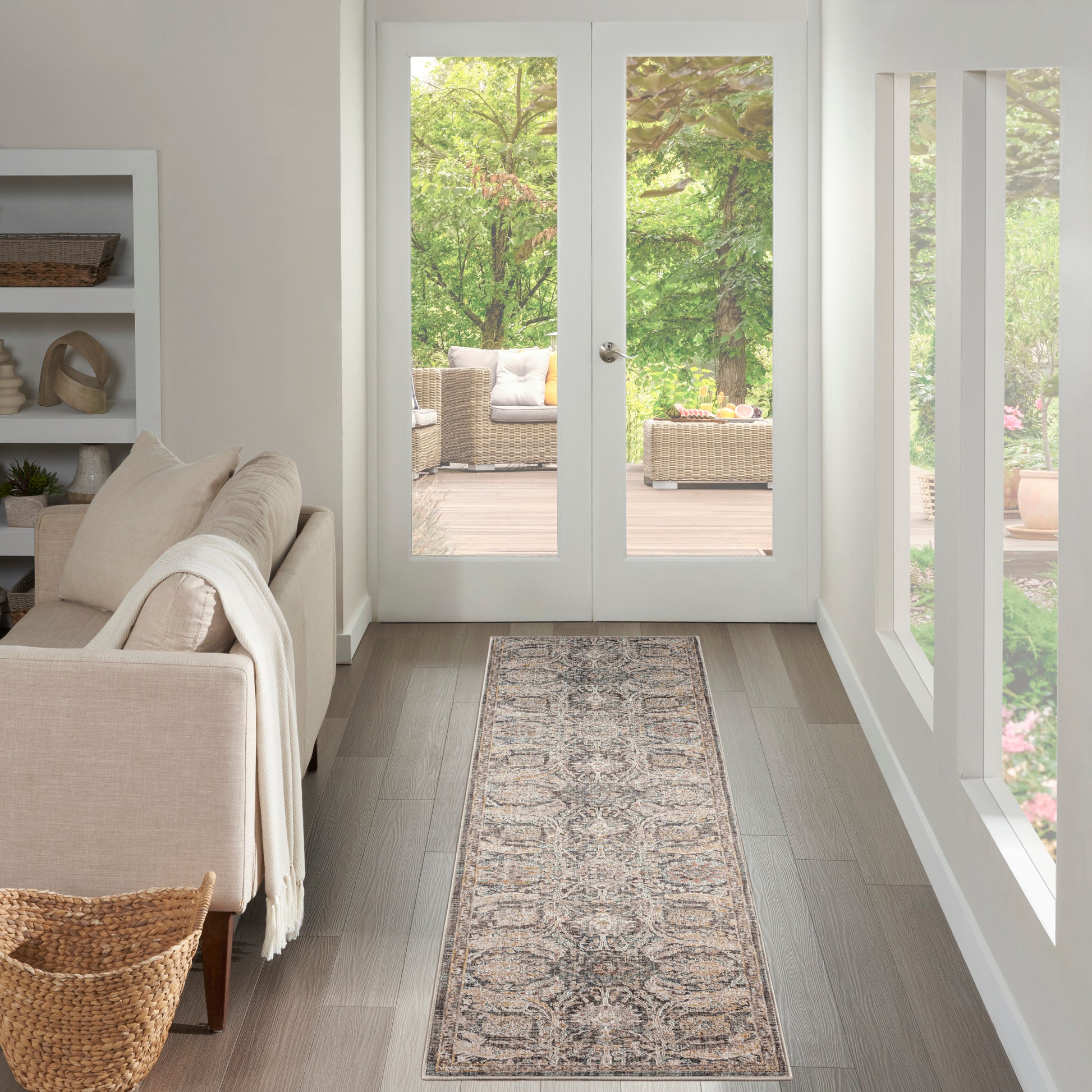 Neutral living room with cream sofa, throw, built-in shelf, runner rug, wood floor, and French doors to a wicker patio.