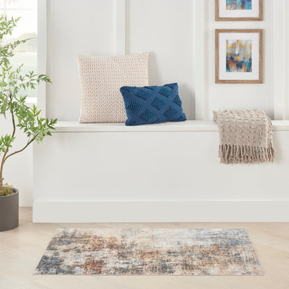 Cream knit cushion, blue diamond-knit pillow on a white window seat with beige fringe throw and abstract art rug.
