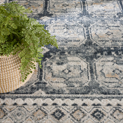 Green fern in a round woven basket on a blue and beige geometric-pattern rug.