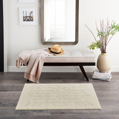 Neutral entryway with tufted cream bench, beige throw, hat, large wood-framed mirror, vase of branches, and geometric rug.